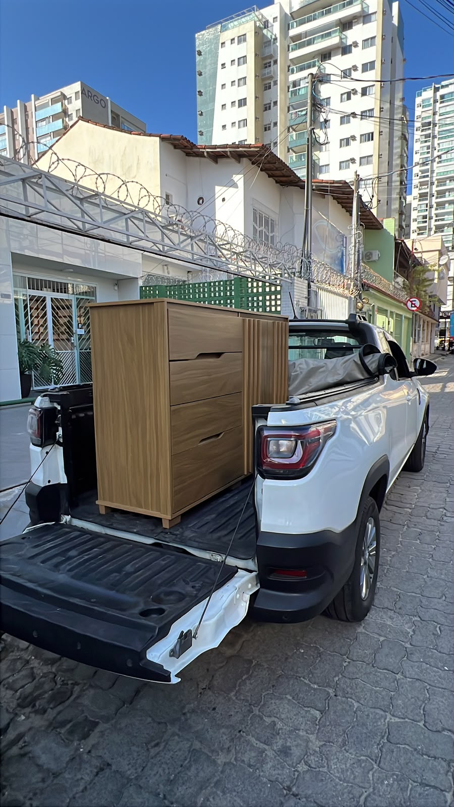 Cômoda transportada na caçamba da Strada em área urbana